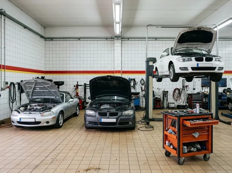 Três carros nos elevadores numa oficina clara de azulejo branco