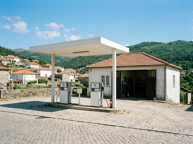 A cobertura de um posto de combustível numa rua de calçada ao sol, à frente da oficina